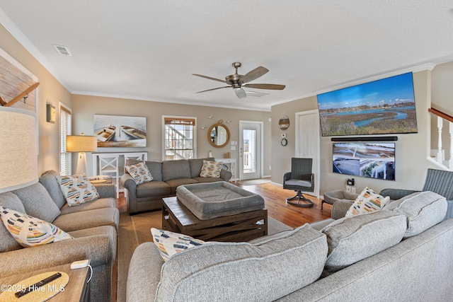 living room featuring a ceiling fan, wood finished floors, visible vents, and crown molding