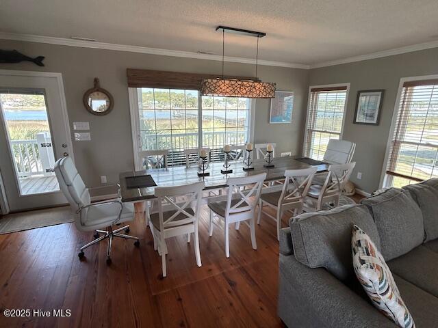 dining space featuring a textured ceiling, wood-type flooring, baseboards, and crown molding