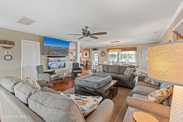 living area with crown molding, decorative columns, visible vents, a ceiling fan, and wood finished floors