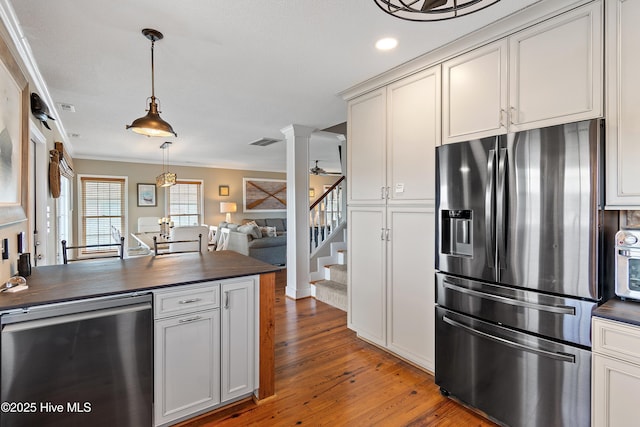 kitchen with stainless steel appliances, wood finished floors, visible vents, open floor plan, and decorative columns