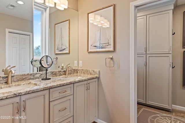 bathroom featuring double vanity, baseboards, visible vents, and a sink