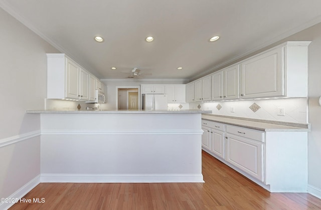 kitchen featuring light wood-style floors, refrigerator, light countertops, and white cabinetry