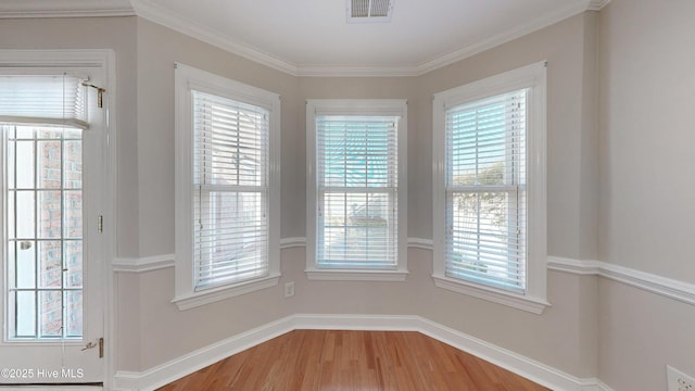 unfurnished dining area with baseboards, crown molding, visible vents, and wood finished floors