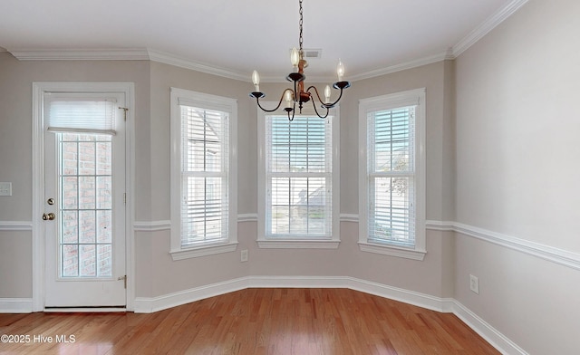 unfurnished dining area featuring a notable chandelier, wood finished floors, visible vents, baseboards, and crown molding