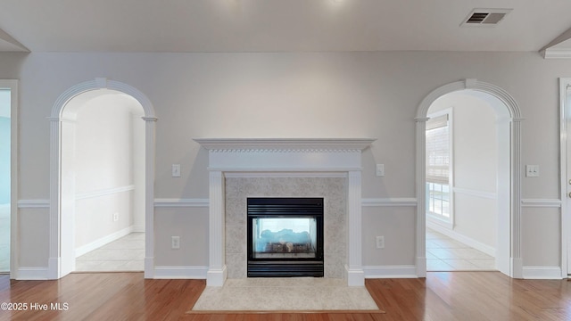 interior space featuring baseboards, wood finished floors, visible vents, and a multi sided fireplace