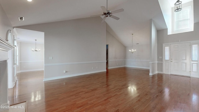 unfurnished living room with ceiling fan with notable chandelier, high vaulted ceiling, wood finished floors, and visible vents