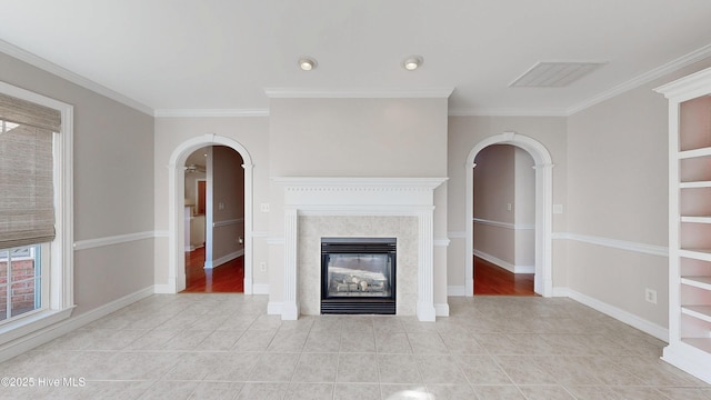 unfurnished living room with arched walkways, tile patterned flooring, a fireplace, baseboards, and ornamental molding