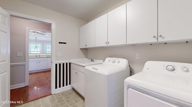 laundry area featuring a sink, washing machine and dryer, cabinet space, and light wood-style floors