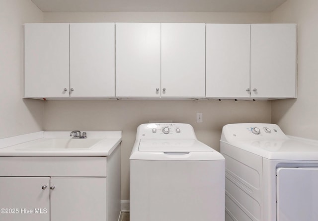 laundry area with washer and clothes dryer, a sink, and cabinet space