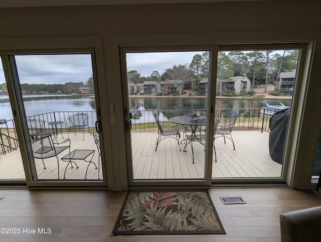 doorway to outside featuring a water view, plenty of natural light, visible vents, and wood finished floors