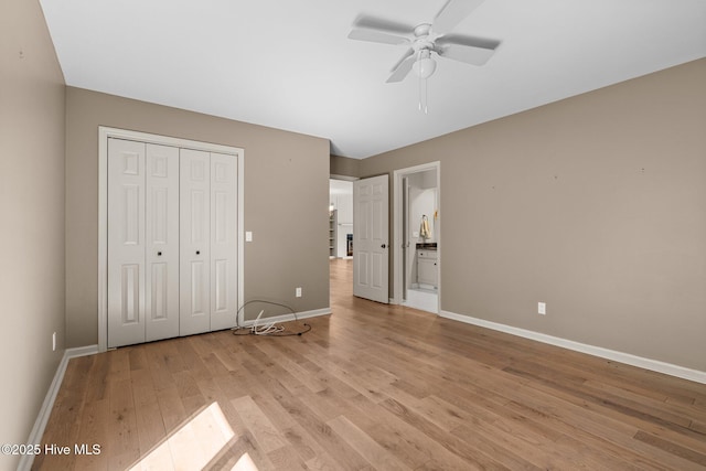 unfurnished bedroom featuring ensuite bathroom, ceiling fan, light wood-style flooring, baseboards, and a closet