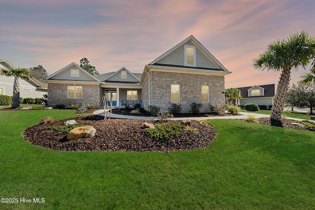 view of front of home featuring brick siding and a lawn