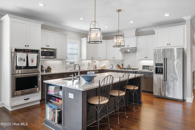 kitchen featuring stainless steel appliances, a center island with sink, under cabinet range hood, and dark wood-style floors