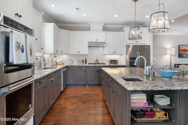 kitchen with under cabinet range hood, appliances with stainless steel finishes, open shelves, and a sink