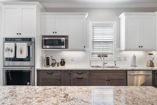 kitchen featuring crown molding, decorative backsplash, stainless steel appliances, and a sink