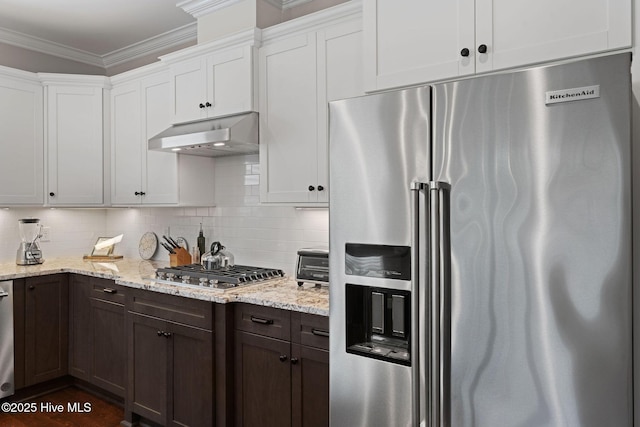 kitchen featuring under cabinet range hood, ornamental molding, stainless steel appliances, and backsplash