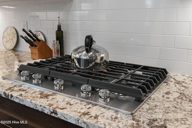 interior details with stainless steel gas cooktop, decorative backsplash, and light countertops