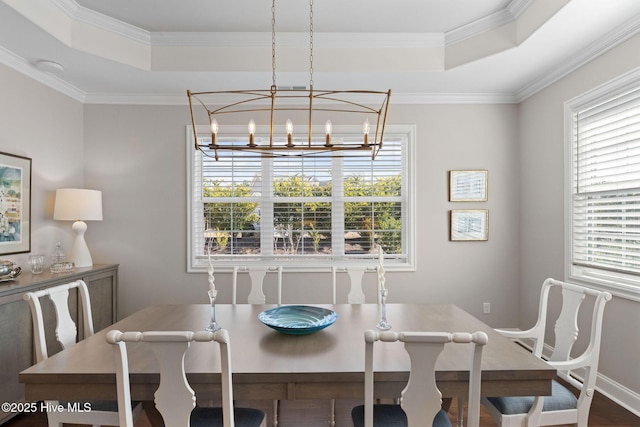 dining area featuring ornamental molding, a tray ceiling, and an inviting chandelier