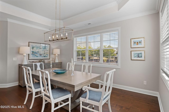 dining area featuring ornamental molding, dark wood-type flooring, and a raised ceiling