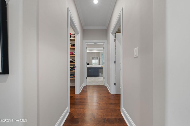 hall featuring dark wood-style floors, baseboards, and crown molding