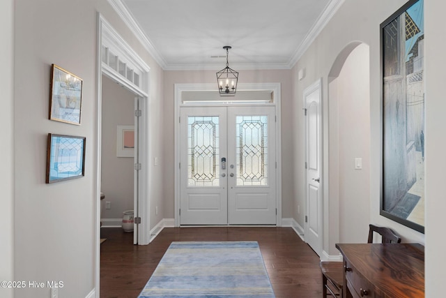 foyer entrance with arched walkways, french doors, dark wood-type flooring, ornamental molding, and baseboards