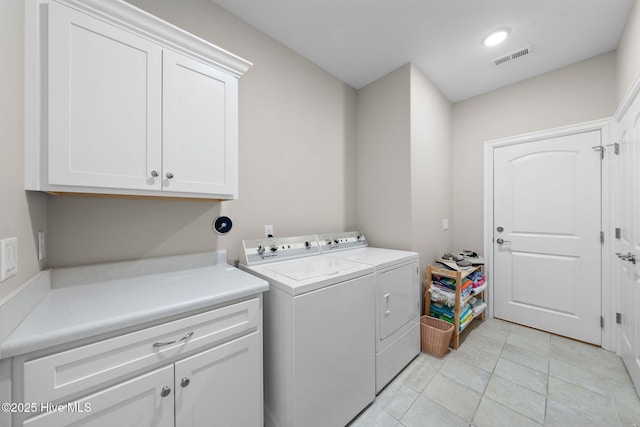 laundry area with visible vents, light tile patterned flooring, washing machine and dryer, and cabinet space