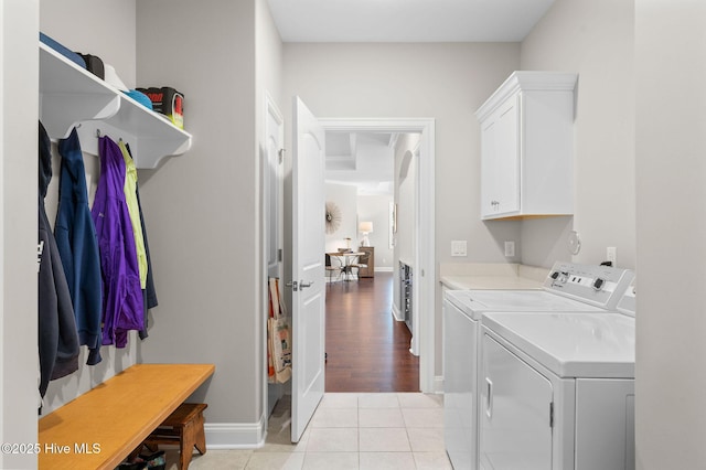 laundry area with cabinet space, independent washer and dryer, baseboards, and light tile patterned floors