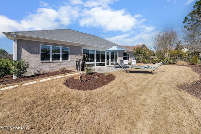 rear view of house featuring brick siding, a lawn, and a patio area