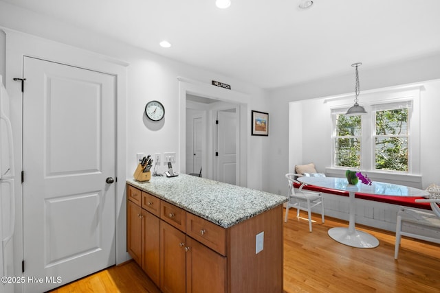 kitchen featuring a peninsula, light wood-style flooring, breakfast area, and brown cabinetry