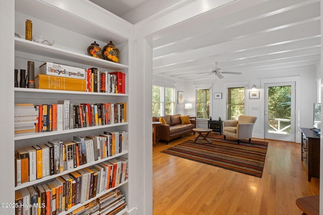 sitting room with ceiling fan, beam ceiling, and wood finished floors