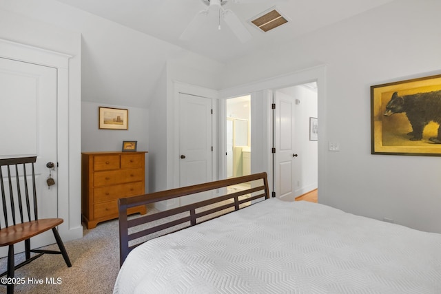 bedroom featuring lofted ceiling, visible vents, a ceiling fan, light carpet, and ensuite bath