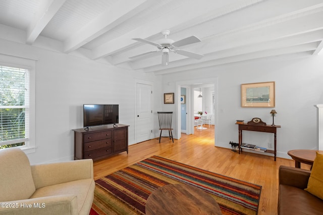 living room with light wood finished floors, a ceiling fan, baseboards, and beamed ceiling