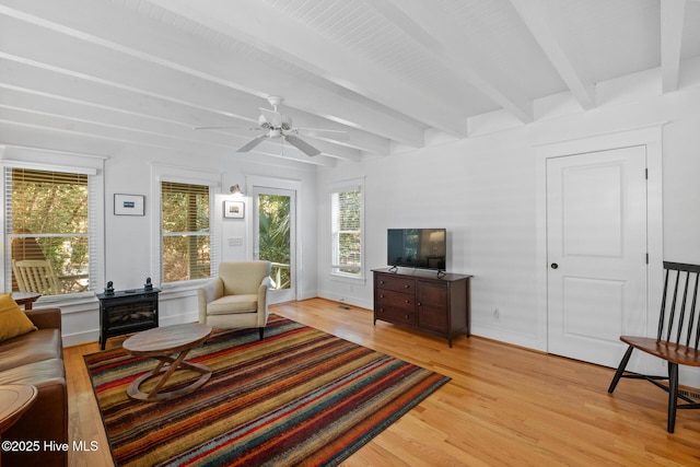 living area with ceiling fan, light wood finished floors, beamed ceiling, and baseboards