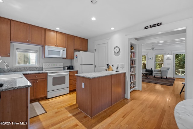 kitchen with a wealth of natural light, white appliances, a sink, and light wood-style flooring