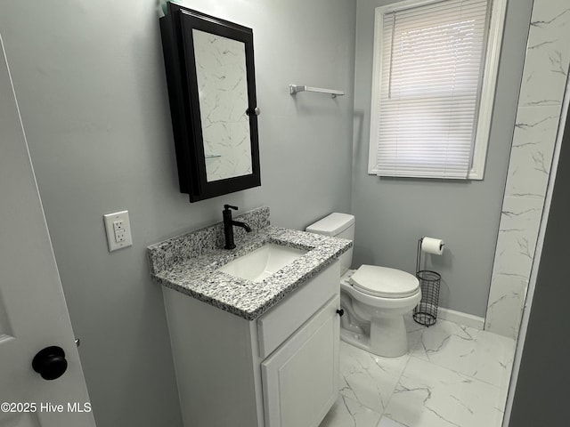 bathroom featuring marble finish floor, baseboards, vanity, and toilet