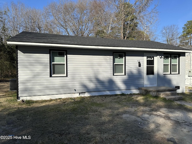 view of front of house featuring roof with shingles, brick siding, crawl space, and a front yard