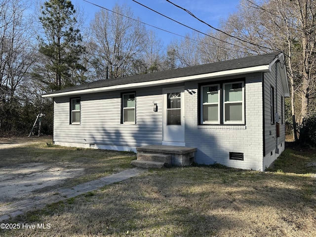 view of front of property featuring crawl space, brick siding, driveway, and a front lawn