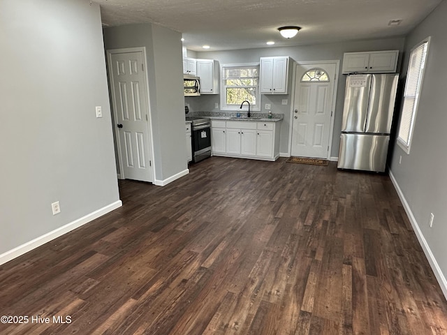 kitchen with a sink, white cabinets, baseboards, light countertops, and appliances with stainless steel finishes