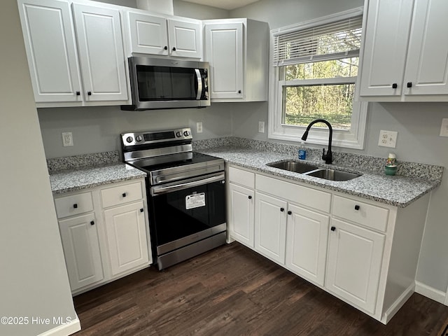 kitchen featuring appliances with stainless steel finishes, dark wood-type flooring, a sink, and white cabinets