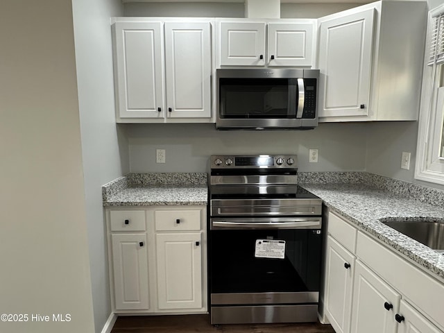 kitchen featuring stainless steel appliances, dark wood finished floors, white cabinetry, and light stone countertops