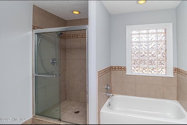 bathroom featuring a bath, a shower stall, and a textured ceiling