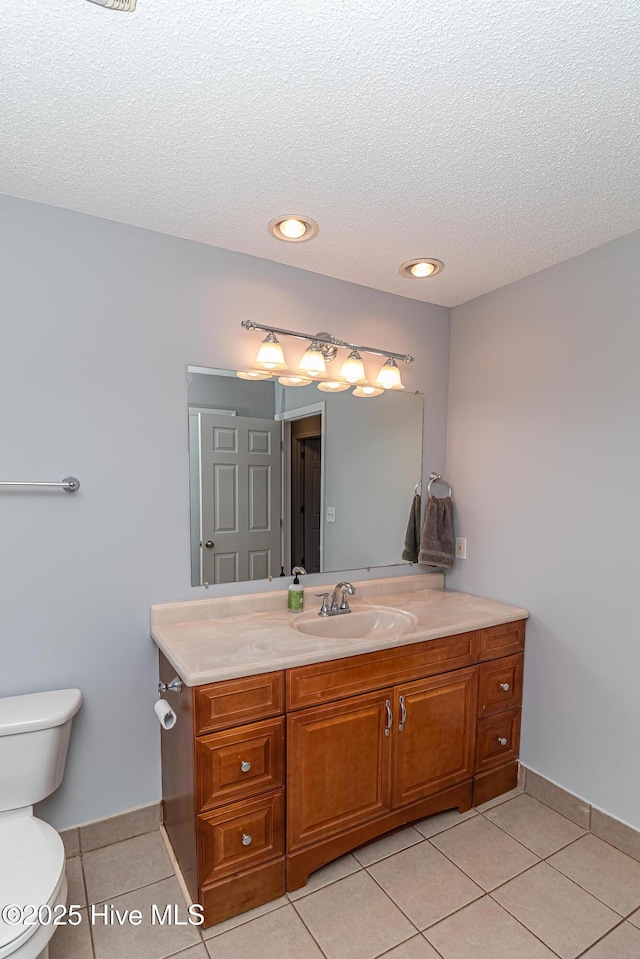 bathroom with a textured ceiling, vanity, toilet, and tile patterned floors