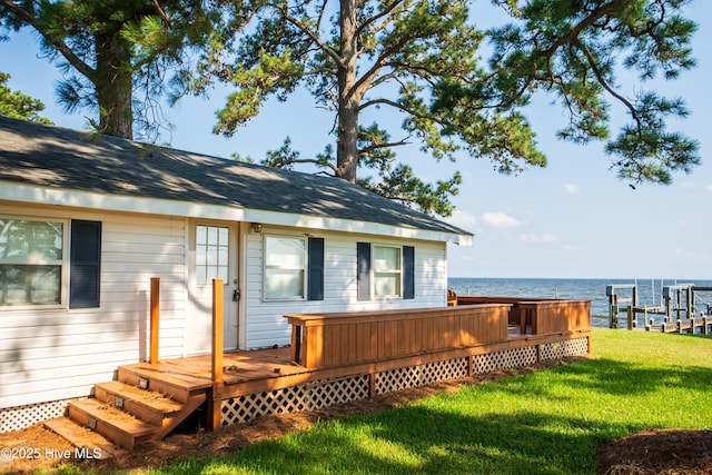 wooden deck featuring a lawn, a water view, and a dock