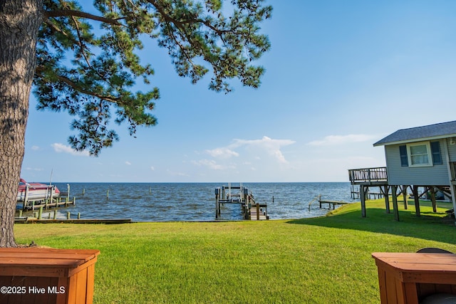 view of yard with a dock, a water view, and boat lift