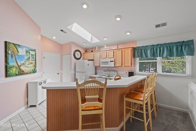 kitchen with light countertops, white appliances, lofted ceiling with skylight, and visible vents