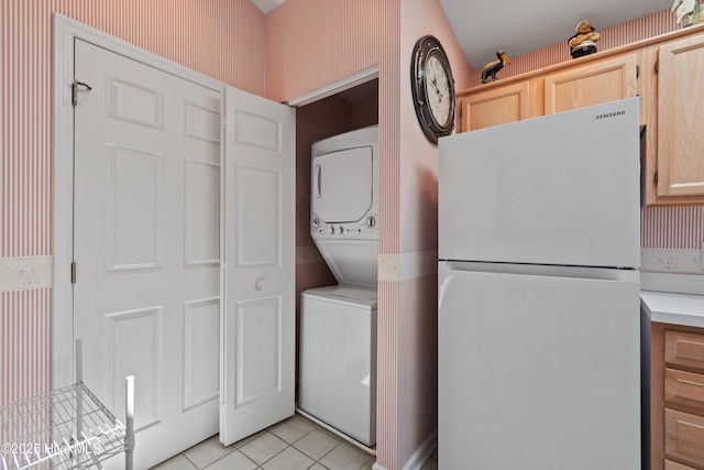 clothes washing area featuring stacked washer and dryer, laundry area, wallpapered walls, and light tile patterned floors