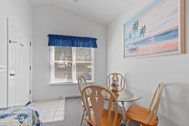 carpeted dining area with baseboards and vaulted ceiling