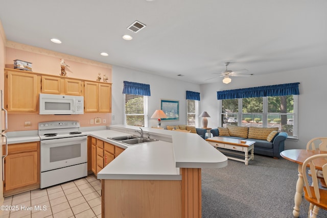 kitchen with a peninsula, white appliances, a sink, visible vents, and light brown cabinetry