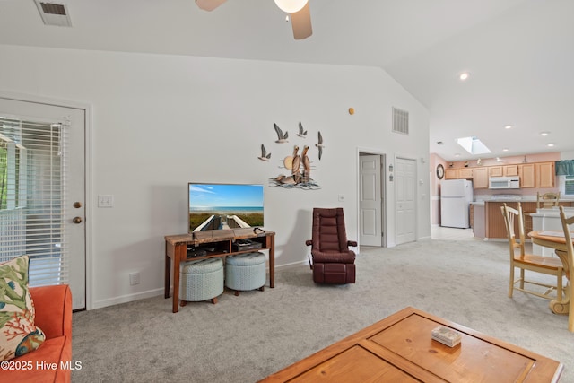 living area with a skylight, visible vents, a ceiling fan, and light colored carpet