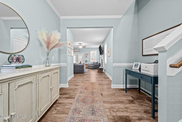 hall with crown molding, light wood-style floors, and baseboards